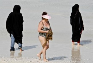 A western woman at a Dubai beach surrounded by women in traditional garb. (Karim Sahib/AFP/Getty Images)