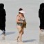 A western woman at a Dubai beach surrounded by women in traditional garb.