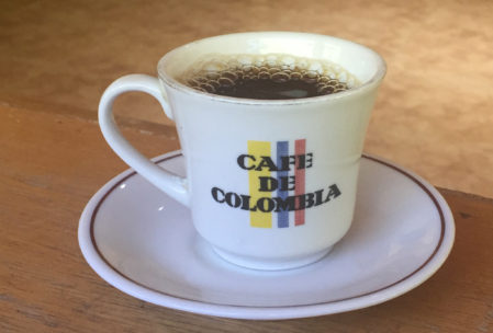 a steaming cup of hot coffee in a cup that says "cafe de colombia"